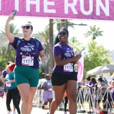 Participant takes a selfie of her and a friend crossing the finish line